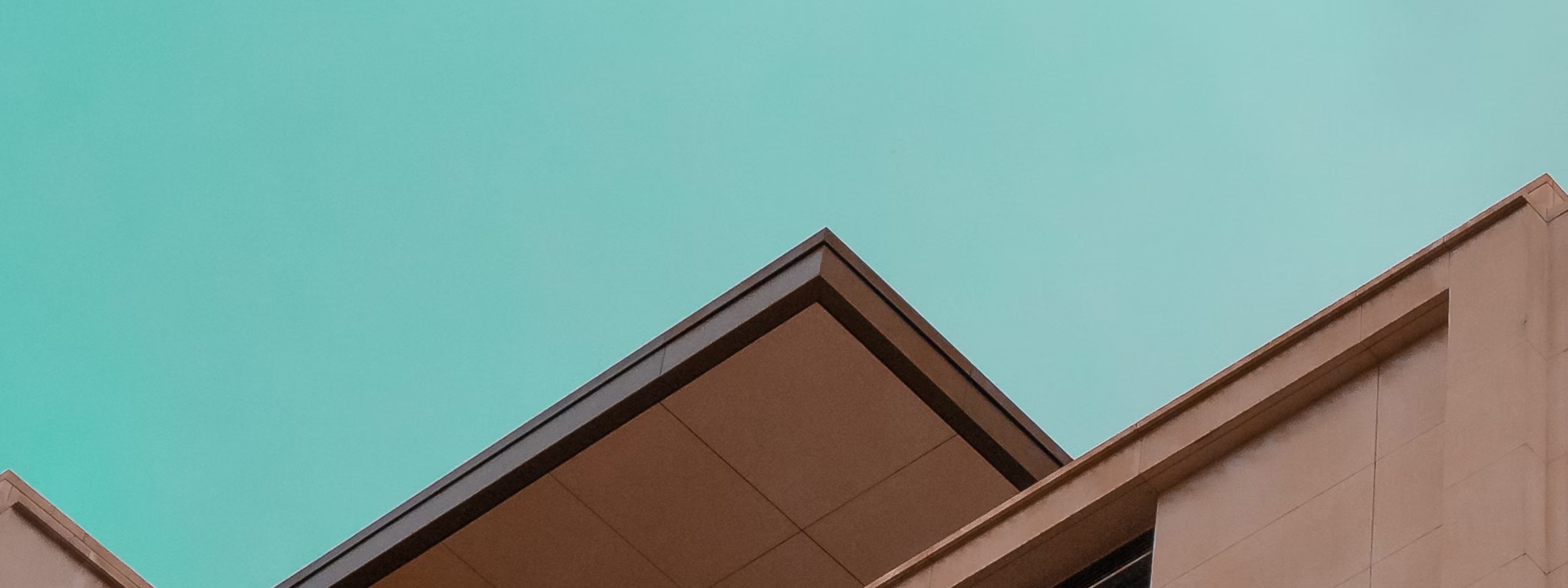 Modern building rooflines against turquoise sky with geometric architectural shapes