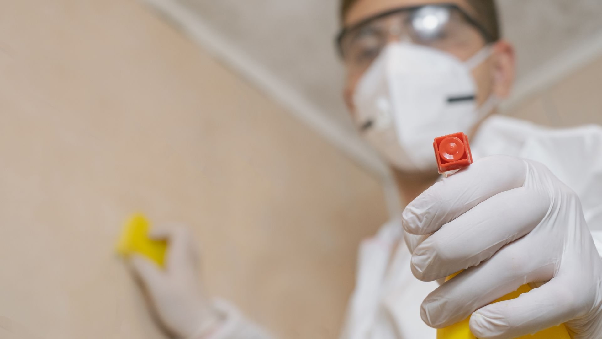 Laboratory worker in protective gear holding red-capped test tube